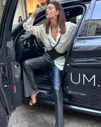 Model trägt schwarzes Lederaccessoire über eleganter Bluse beim Aussteigen aus schwarzem Auto – XMORENIUM-NERO