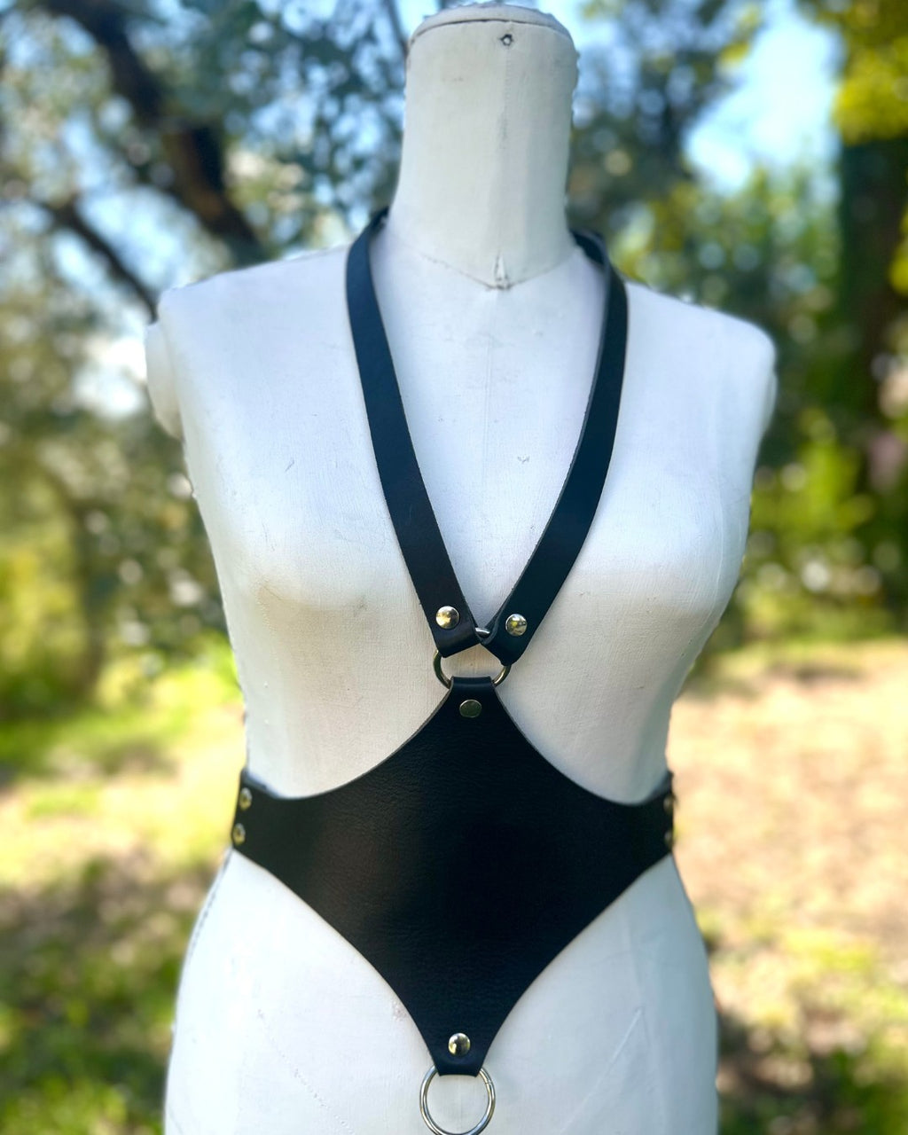 Schwarzes Lederaccessoire mit silbernen Ringen und Nieten auf Schneiderpuppe  von vorne – XMORENIUM-NERO