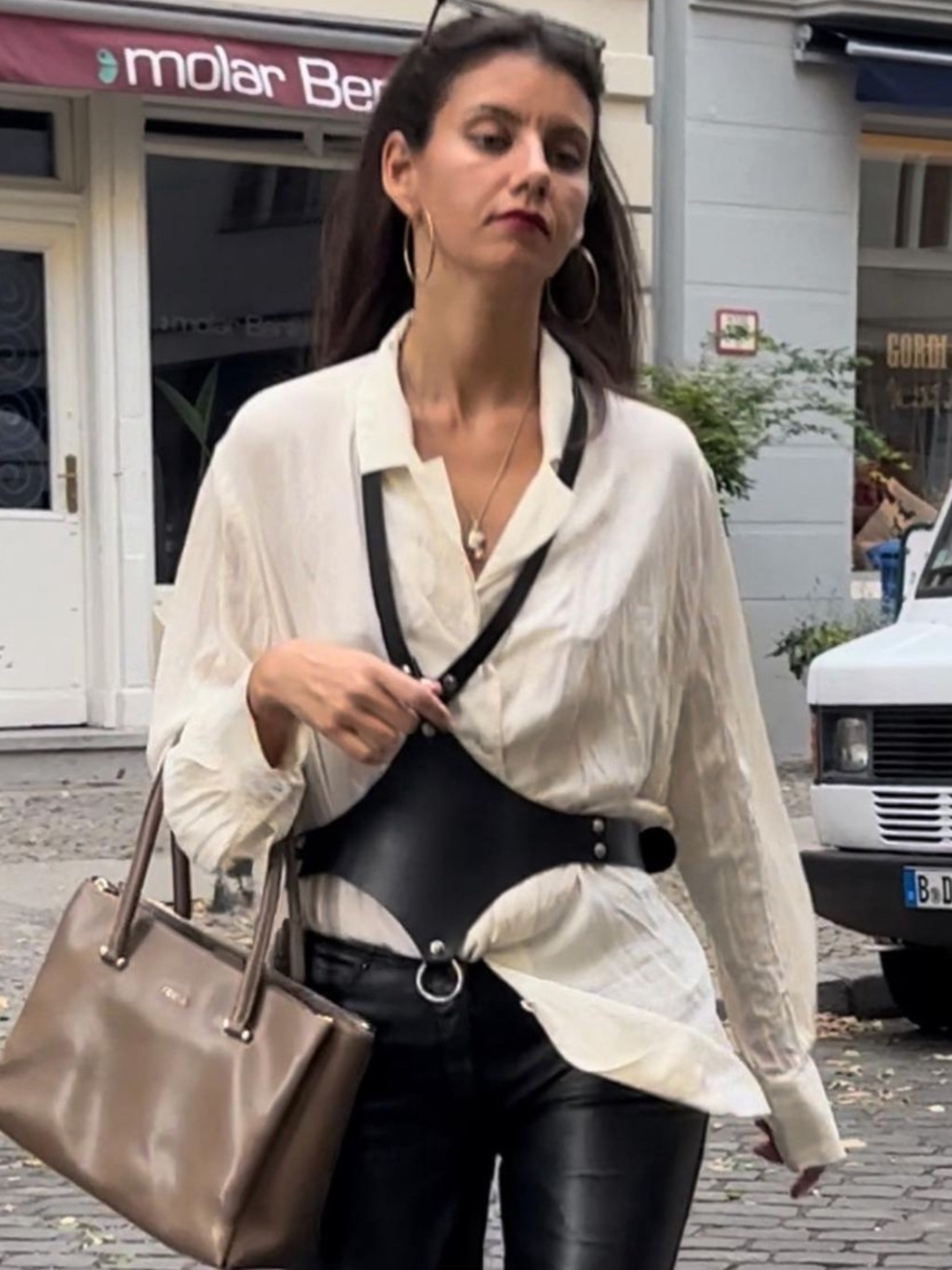 Model trägt BlackDominian, schwarzes Lederaccessoire zur Leder Hose über beiger Bluse, casual Look- XMORENIUM-NERO