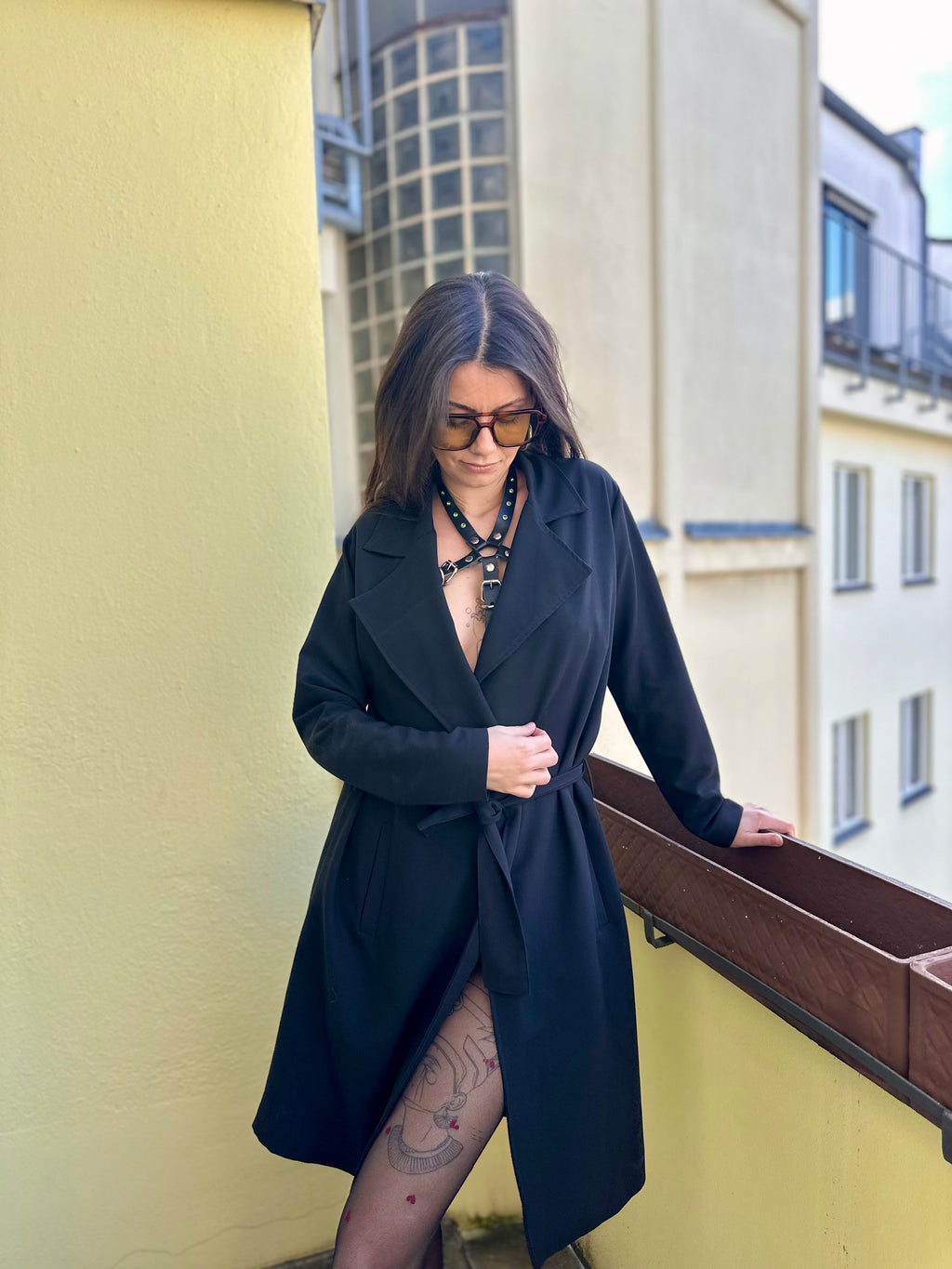 BlackTulip Leder Accessoire in Schwarz  - veredelt mit grünem Strass, auf der Haut unter einem schwarzen Mantel. 
Eleganter Stil. Hier blitzt der obere Teil des  BlackTulips mit seinem grünen Strass  auf. Ganzkörperaufnahme  - XMORENIUM-NERO