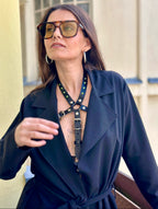 BlackTulip Leder Accessoire in Schwarz  - veredelt mit grünem Strass, auf der Haut unter einem schwarzen Mantel. 
Eleganter Stil. Hier blitzt der obere Teil des  BlackTulips mit seinem grünen Strass  auf. Nahaufnahme  - XMORENIUM-NERO