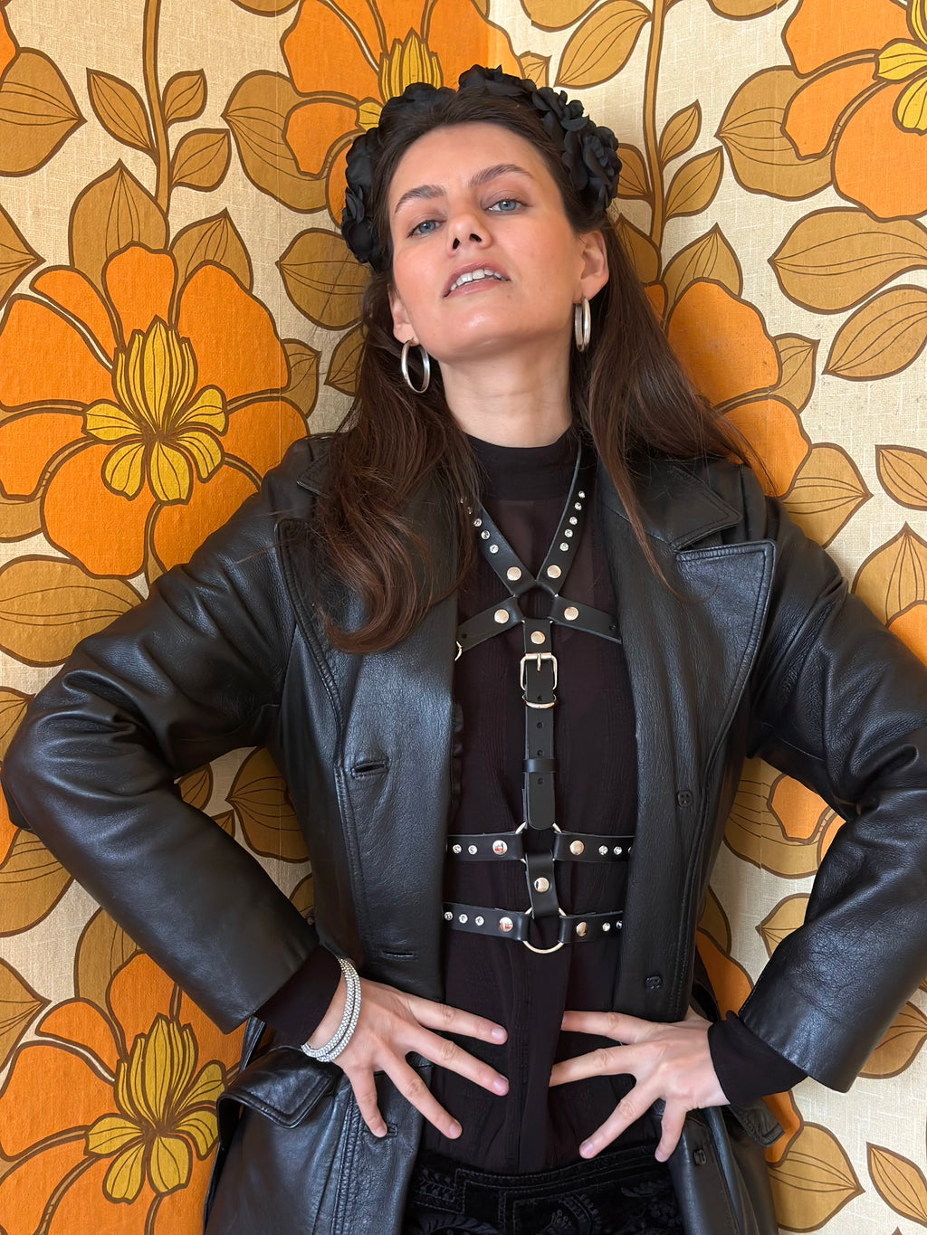 BlackTulip Leder Accessoire mit weißem Strass veredelt, über einem schwarzen Kleid und Ledermantel darüber , die Dame steht - XMORENIUM-NERO