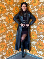 BlackTulip Leder Accessoire mit weißem Strass veredelt, über einem schwarzen Kleid und schwarzem Ledermantel darüber , Stiefel, Ganzkörperaufnahme - XMORENIUM-NERO