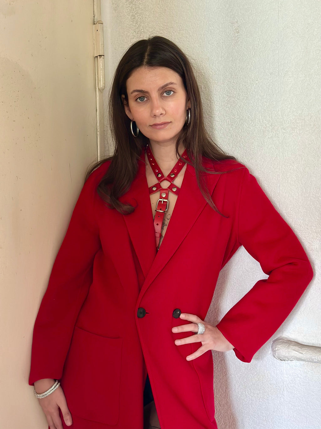 RedTulip Leder Accessoire in Rot mit Rotem Strass veredelt, auf der Haut unter einem roten Mantel. Hier blitzt der obere Teil des  RedTulip RedDiamant mit seinem Strass auf. Ganzkörperaufnahme, elegant und casual - XMORENIUM-NERO