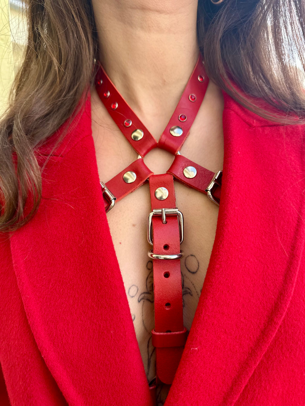 RedTulip Leder Accessoire in Rot mit Rotem Strass veredelt, auf der Haut unter einem roten Mantel. Hier blitzt der obere Teil des  RedTulip RedDiamant mit seinem Strass auf. Detailaufnahme des oberen Teils mit rotem Strass  -  XMORENIUM-NERO