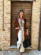 RedTulip Leder Accessoire in Rot  - das Basis Modell, auf der Haut unter einer beigen Satinbluse, dazu eine weiße Hose, einen leichten braunen Sommermantel darüber und eine schwarze Handtasche. Und natürlich Highheels. Eleganter Stil. Hier blitzt der obere Teil des  RedTulip  auf. Ganzkörperaufnahme  - XMORENIUM-NERO