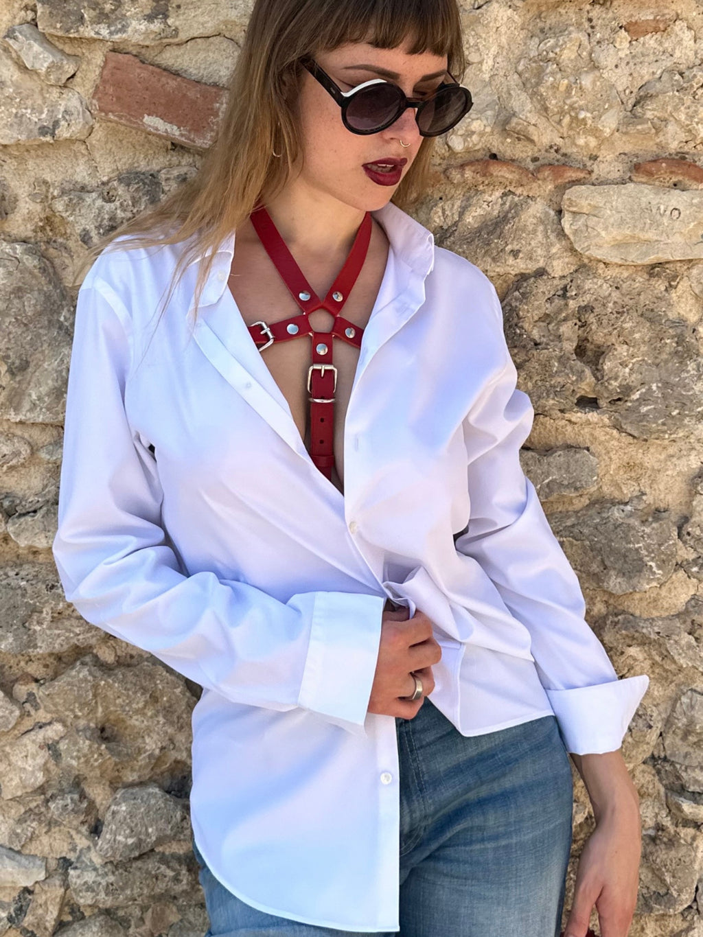 RedTulip Leder Accessoire in Rot  - das Basis Modell, auf der Haut unter einer weißen Bluse, dazu Jeans und Sonnenbrille. Casual und elegant zugleich. Hier blitzt der obere Teil des  RedTulip  auf.  Nahaufnahme  - XMORENIUM-NERO