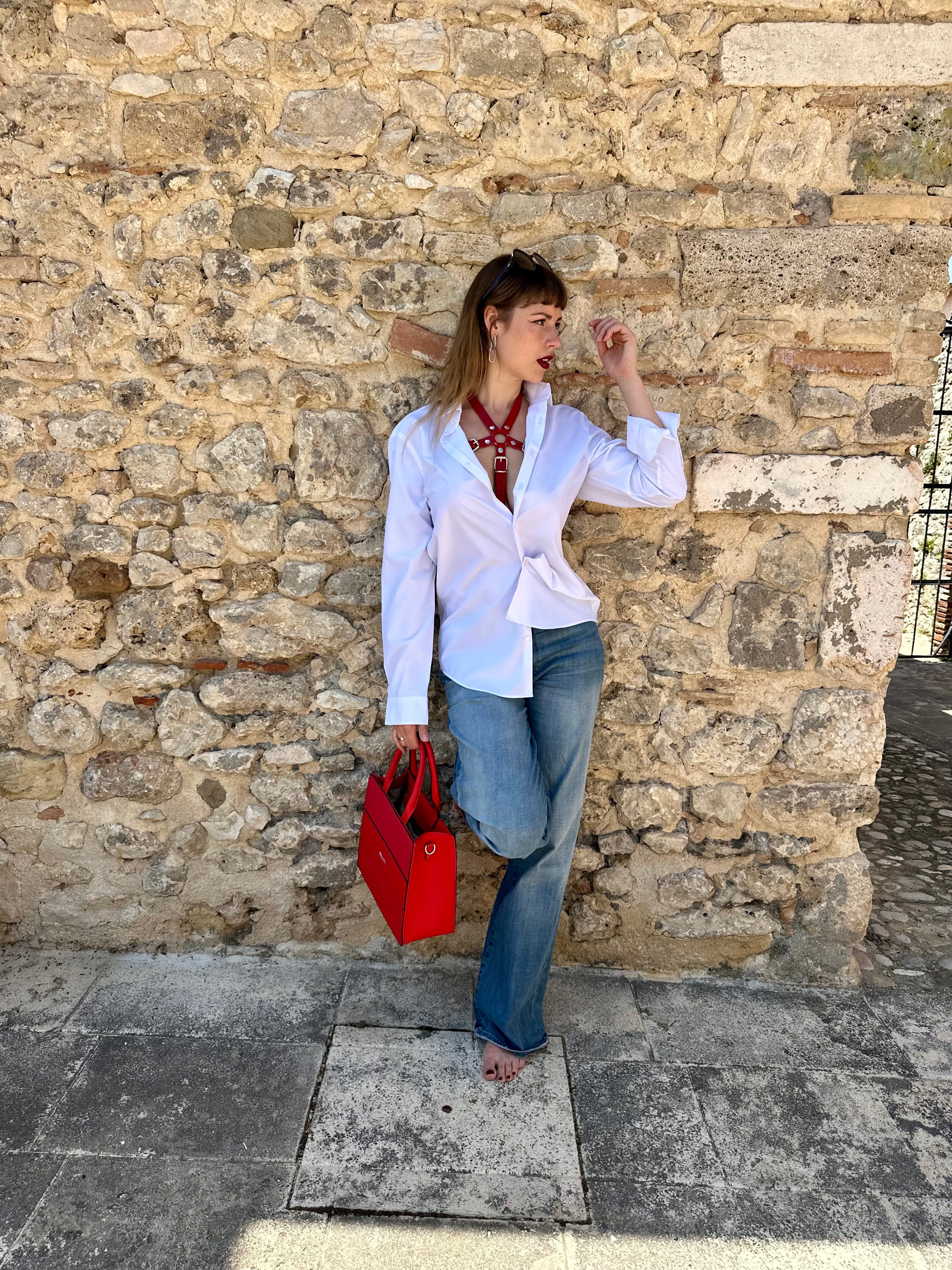 RedTulip Leder Accessoire in Rot  - das Basis Modell, auf der Haut unter einer weißen Bluse, dazu Jeans und eine rote Handtasche. Casual und elegant zugleich. Hier blitzt der obere Teil des  RedTulip  auf.   - XMORENIUM-NERO