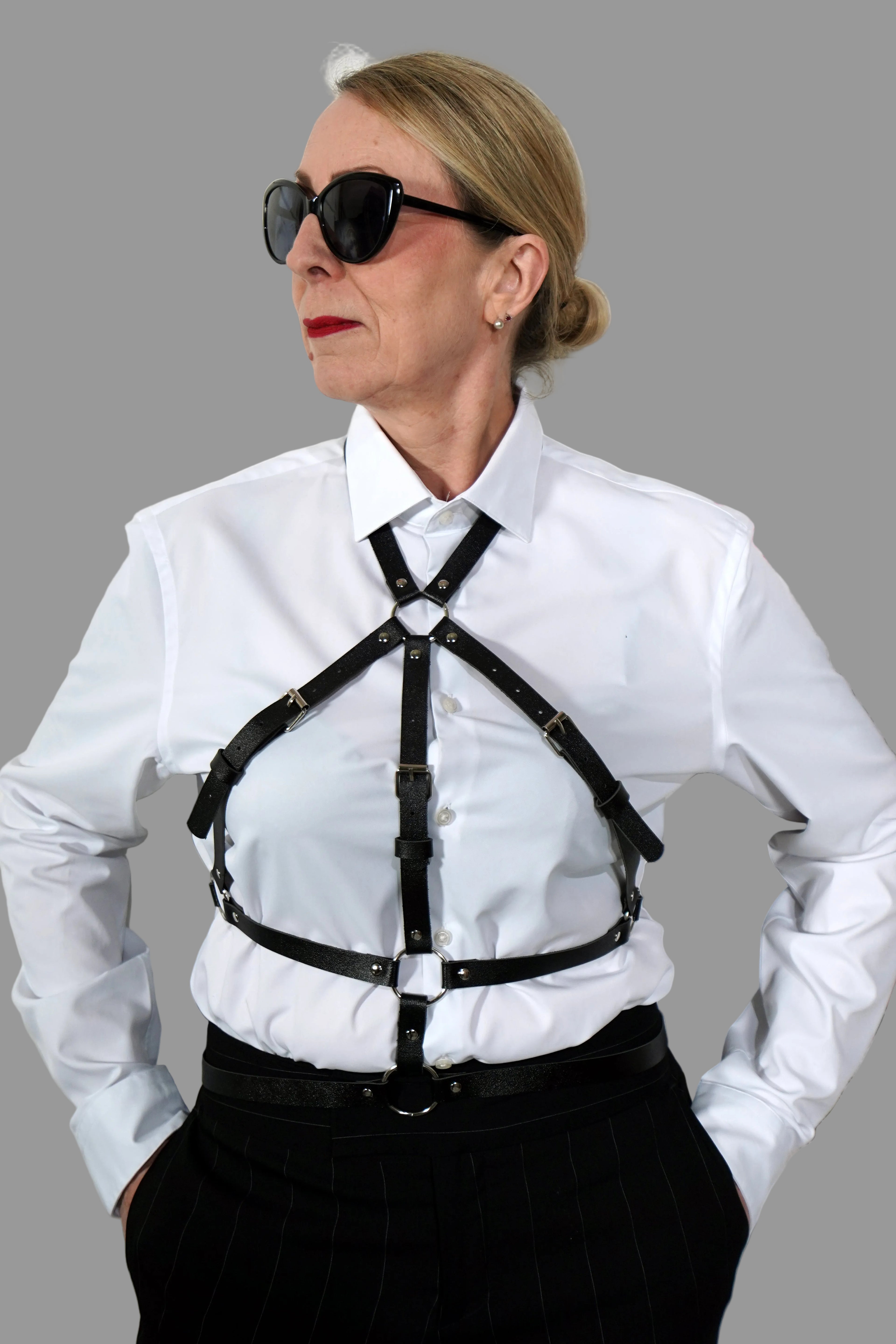 Accessoire aus schwarzem italienischem Leder bestehend aus Riemen getragen über einer weißen Bluse